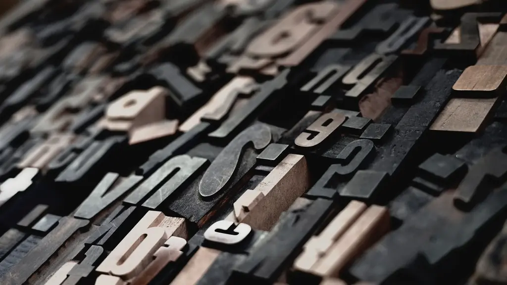 A dense field of wooden letterpress type lying face up, dozens of different letterforms in dark and pale wood.